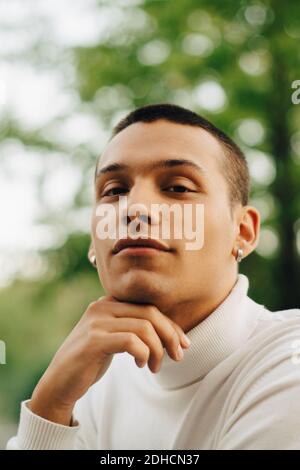 Close-up portrait of young man with hand on chin Stock Photo