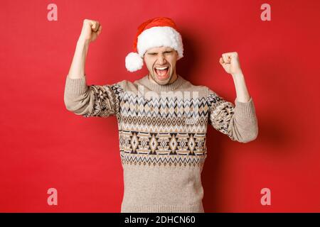 Satisfied handsome man, feeling lucky and happy, shouting for joy and making fist pumps, celebrating victory or win, receive awe Stock Photo