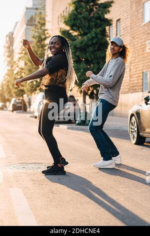 Full length of smiling friends dancing on road at city Stock Photo