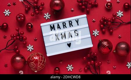 Concept of Marry Christmas banner.White scoreboard with text lettering Marry Xmas among Christmas red decor, balls, berries, stars and white snowflake Stock Photo