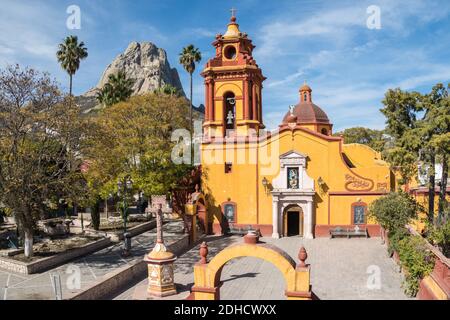 The Parroquia San Sebastian church with the massive monolith rock called the Pena de Bernal in the beautiful colonial village of Bernal, Queretaro, Mexico. Bernal is a quaint colonial town known for the Pena de Bernal, a giant monolith which dominates the tiny village is the third highest on the planet. Stock Photo