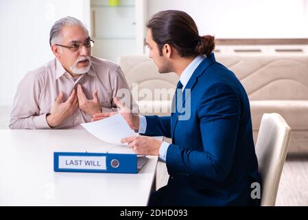 Young male lawyer visiting old man in testament concept Stock Photo