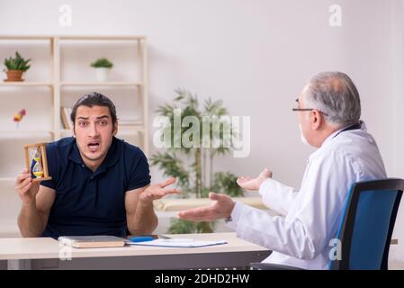 Young male patient visiting old doctor in time management concep Stock Photo