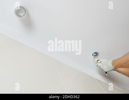 A worker is installing an LED spotlight on the suspended ceiling. Stock Photo