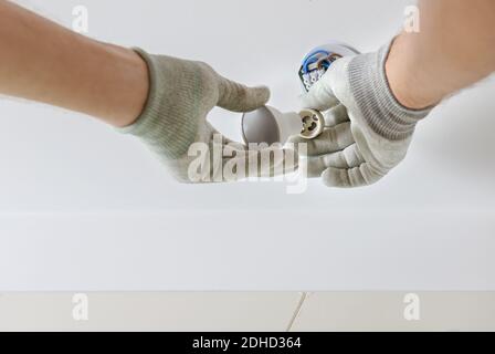 A worker is installing an LED spotlight on the suspended ceiling. Stock Photo