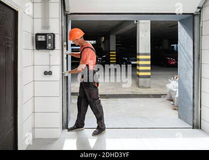 The worker is checking with the water level the vertical guide of the lift gate. Stock Photo
