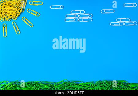 Made of colored bright paper clips on blue background,top view with copy space for text or creativity.Sunny day,blue sky,clouds,grass Stock Photo