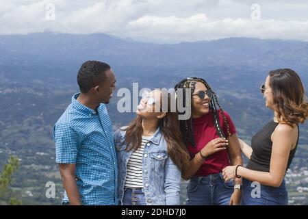group of four Latin American adventurers friends outdoors smiling using sunglasses in a rural landscape mountain place in dominican republic in a summ Stock Photo