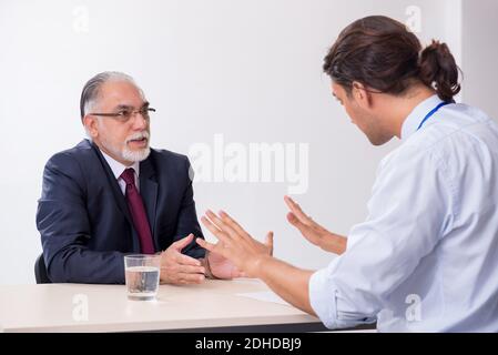 Old businessman meeting with advocate in pre-trial detention Stock Photo