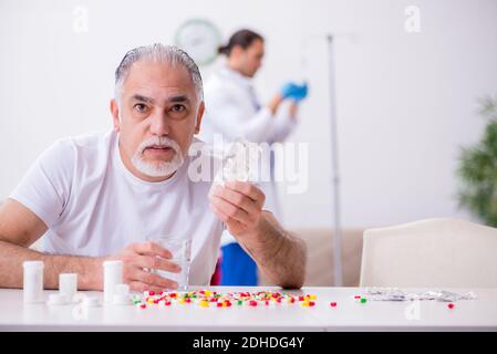 Young male doctor visiting old male patient at home Stock Photo