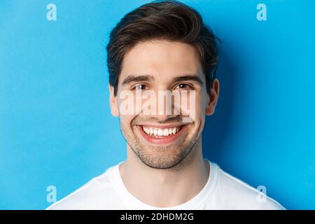 Head shot of handsome young man with beard, smiling happy over blue background. Copy space Stock Photo