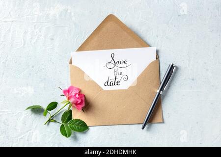 Save the date lettering on an invitation in a brown kraft envelope, shot from above Stock Photo