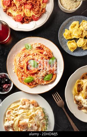 Pasta dishes variety. Pastas with meat, vegetables, seafood and mushrooms, with ravioli, grated Parmesan cheese, and wine, top s Stock Photo