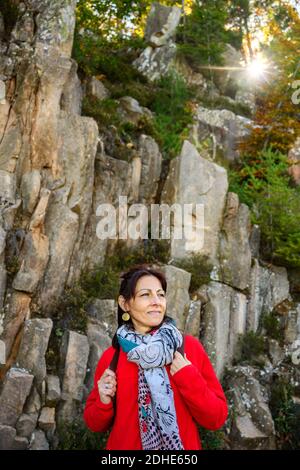 Laughing hiker woman with scarf and backpack, against stone formation Stock Photo