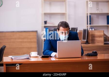 Young male employee working in the office wearing mask Stock Photo
