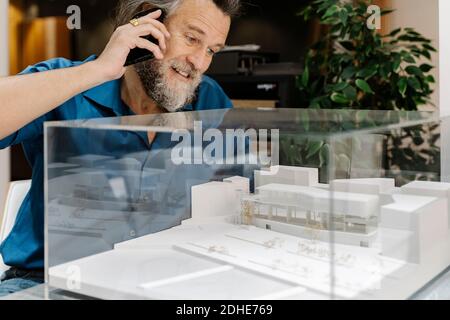 Mature man with a beard talking on the phone and looking at a model of Stock Photo