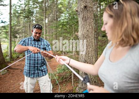 African American male set up tent poles with female friend, camping Stock Photo