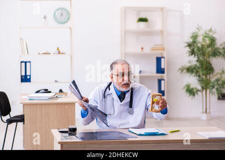 Old male doctor radiologist in time management concept Stock Photo