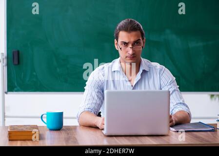 Young male teacher in tele-education concept in the classroom Stock Photo