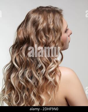 Woman from backside on gray background. Female with curly hair Stock Photo