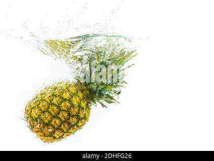 Pineapple is dropped into clear water isolated on white background. Stock Photo