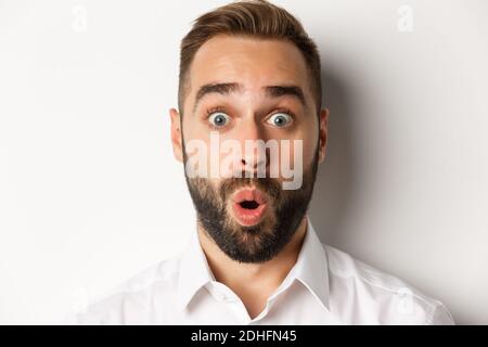 Emotions and people concept. Headshot of man express surprised and amazement, saying wow, standing over white background Stock Photo
