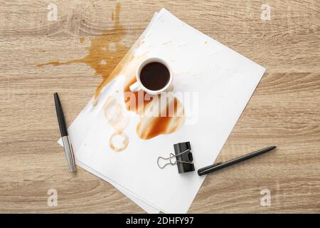 Stationery, cup and spilled coffee on office table Stock Photo