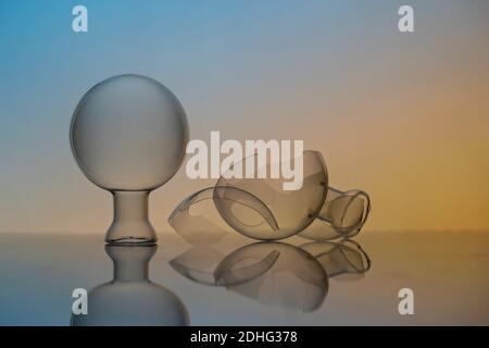 A closeup shot of a crystal ball and broken glass pieces on a glass surface Stock Photo