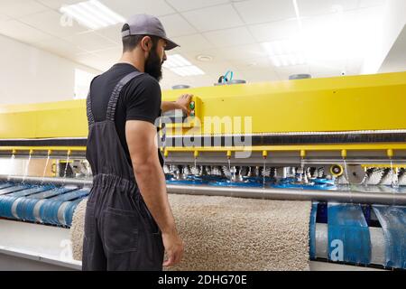 Man operating carpet automatic washing machine in professional laundry service Stock Photo