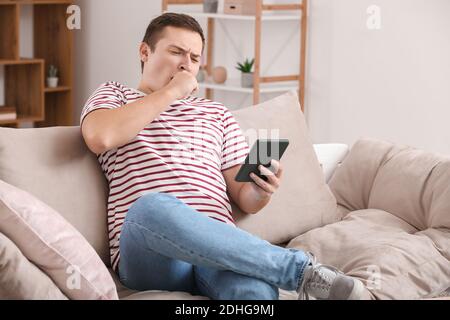 Young man reading boring e-book at home Stock Photo