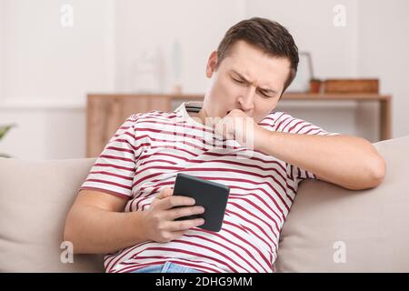 Young man reading boring e-book at home Stock Photo