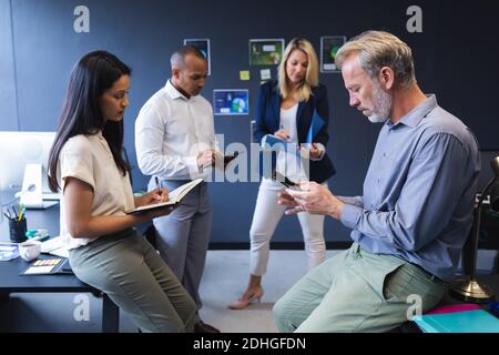 Diverse men and women working in office, writing, using laptop Stock Photo
