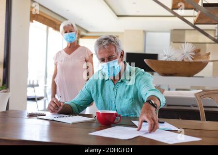 Senior caucasian couple wearing face masks in kitchen