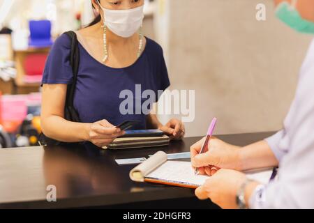 Woman customer in protective mask hand holding credit card at payment counter. Stock Photo
