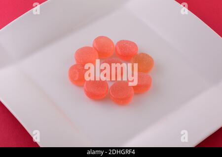 Sweet watermelon gummy candy on white plate on red background Stock Photo