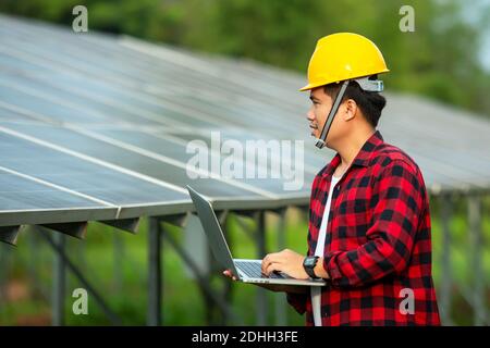 Asian engineer working on checking equipment and use a laptop test solar energy in solar power plant. Stock Photo