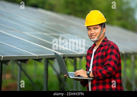 Asian engineer working on checking equipment and use a laptop test solar energy in solar power plant. Stock Photo