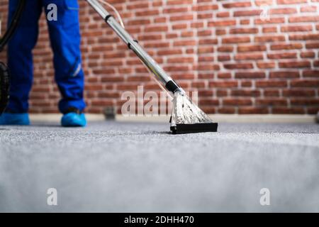 Janitor Cleaning Carpet With Vacuum Cleaner At Home Stock Photo