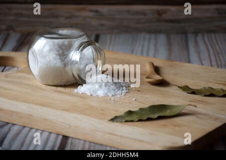 Bay leaf and salt in glass container on wooden background Stock Photo