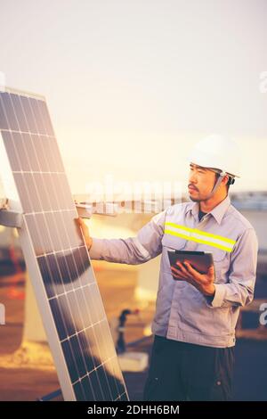 A male engineer holds a tablet to inspect the solar cell system. Stock Photo