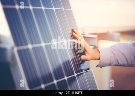 Close up of engineer hand is checking an operation of sun and cleanliness of photovoltaic solar panels on a sunset. Concept: renewable energy, technol Stock Photo