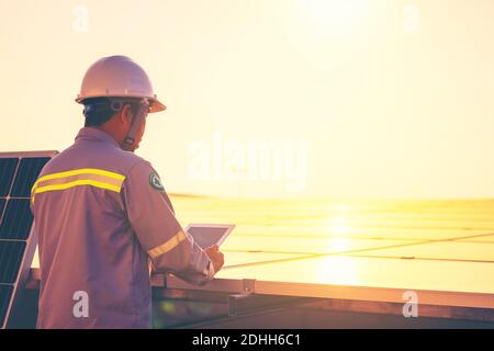 A male engineer holds a tablet to inspect the solar cell system. Stock Photo