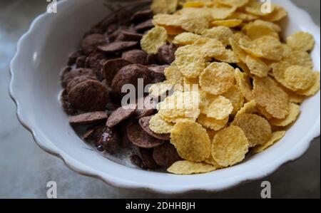 A high angle shot of a bowl of black and yellow cereals on a grey background Stock Photo