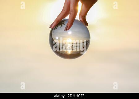 lady catch the crystal ball on her hand beside Patong beach during sunset Stock Photo