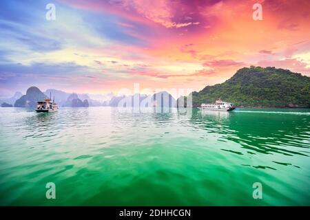 Dreamy sunset in Halong bay, Vietnam. Tourist cruise ship floating among limestone rocks. This is the UNESCO World Heritage Site,