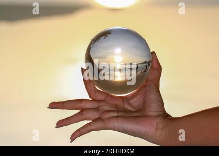 lady catch the crystal ball on her hand beside Patong beach during sunset Stock Photo
