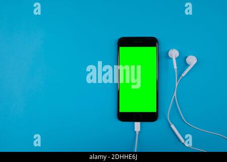 Mobile phone headphones on the blue background . Green screen Stock Photo