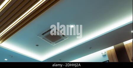 Selective focus on cassette type air conditioner mounted on ceiling wall. Air duct on ceiling in hotel. Air heading unit on gypsum wall. Cool system. Stock Photo