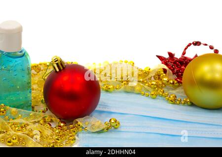 blue medical mask next to Christmas decorations on a white background. Christmas trees, balloons, New year's mood and respiratory protection Stock Photo