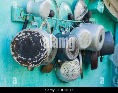Aluminium pots, pans, lids and pots hanging and drying on the wall in russian village at summer season Stock Photo